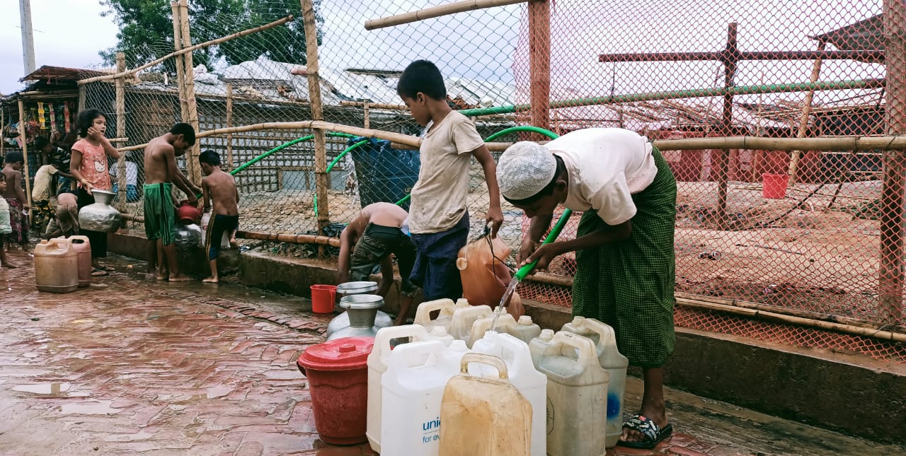 Children filling water containers from a hose